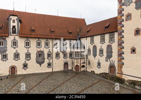 Blick auf eine Ecke des Hinterhofs des Schlosses Hohes Scloss in Füssen an einem bewölkten Wintertag, mit schöner Malerei an der Fassade, Allgäu, Bayern, Deutschland Stockfoto