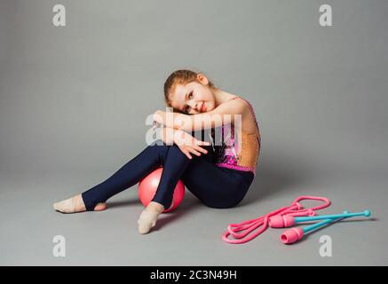 Mädchen Turnerin posiert mit Keule und Seil auf grauem Hintergrund. Stockfoto