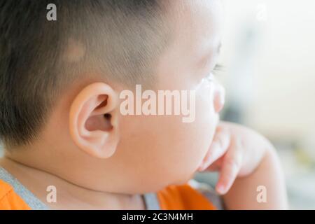 Nahaufnahme des Babygesichts. Ein Junge leckt seinen Finger. Stockfoto