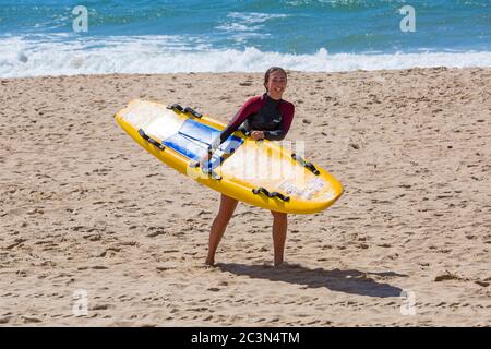 Bournemouth, Dorset, Großbritannien. Juni 2020. An einigen Stränden von Bournemouth sind RNLI-Rettungsschwimmer wieder im Einsatz, da die Temperaturen in der Woche für eine kleine Hitzewelle ansteigen, die Massen an die Strände locken wird. Weibliche RNLI Rettungsschwimmer mit Surfbrett Rettungsschlitten am Strand. Quelle: Carolyn Jenkins/Alamy Live News Stockfoto