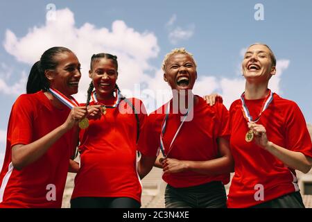 Frau Fußballmannschaft mit Medaillen feiern einen Sieg. Aufgeregt Frau Fußballmannschaft schreien vor Freude nach dem Gewinn der Meisterschaft. Stockfoto