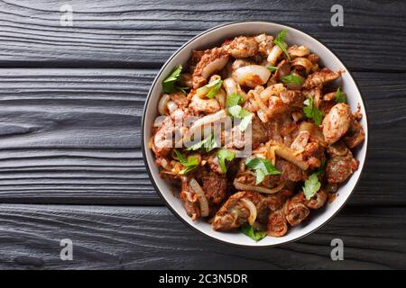 Armenische Tjvjik gebratenes Huhn Innereien Leber, Herz und Mägen mit Zwiebeln, Tomaten und Gewürzen in einer Schüssel auf dem Tisch. Horizontale Draufsicht Fr. Stockfoto