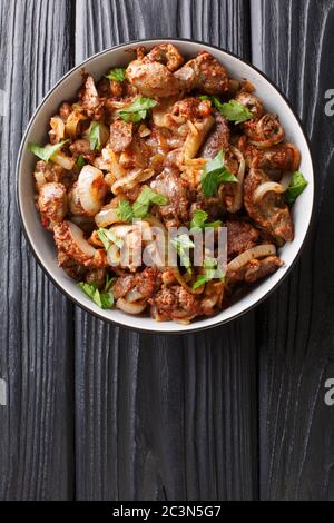 Gebratene Hühnerfleisch Leber, Herz und Mägen mit Zwiebeln, Tomaten und Gewürzen in einer Schüssel auf dem Tisch. Vertikale Ansicht von oben Stockfoto