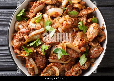 Armenische Küche Rezept Huhn Leber, Herz und Mägen mit Zwiebeln, Tomaten und Gewürzen close-up in einer Schüssel auf dem Tisch. Horizontale Ansicht von oben aus Stockfoto
