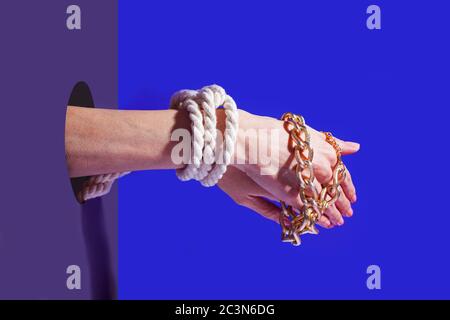 Ein Paar Hände mit Seil und goldener Kette gebunden Stockfoto