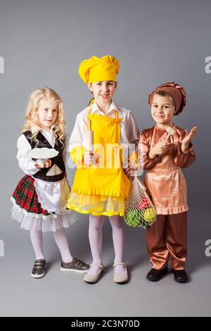 Gruppe von Kindern spielen in Zukunft Beruf. Kinder tragen Kostüme von Koch, Bäcker und Kellner. Stockfoto