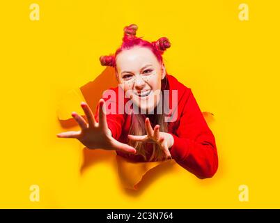 Emotionale junge Frau, die durch ein Loch in einer Wand bricht Stockfoto