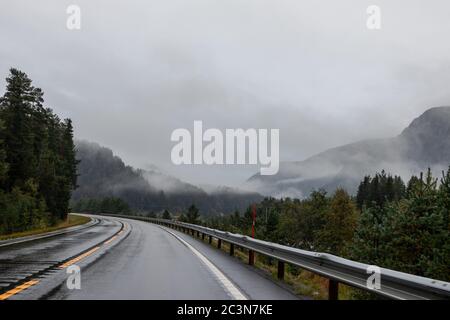 Autobahn in einem nebligen Gebirge von Norwegen. Herbst malerischer Nebel niedrige Wolken auf dem Weg nach Oslo an einem regnerischen nassen Morgen Stockfoto