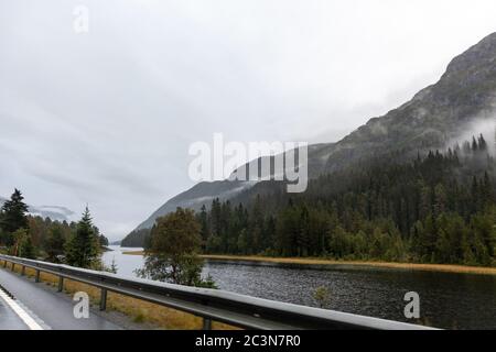 Autobahn in einem nebligen Bergsee in Norwegen. Herbst malerischer Nebel niedrige Wolken auf dem Weg nach Oslo an einem regnerischen nassen Morgen Stockfoto