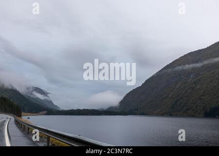 Autobahn in einem nebligen Bergsee in Norwegen. Herbst malerischer Nebel niedrige Wolken auf dem Weg nach Oslo an einem regnerischen nassen Morgen Stockfoto