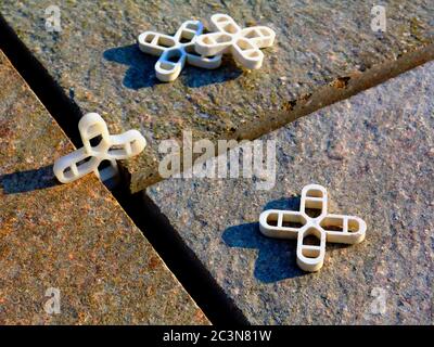 Beton quadratische Fliesen vor dem Verfugen Abstand. Bunte Terrakotta Pflastersteine gelegt. Weiße Kunststoff-Abstandshalter auf top.construction Prozess. Stockfoto