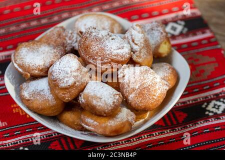 rumänische Mini-Donuts auf einem Teller auf rotem traditionellen Tuch Stockfoto