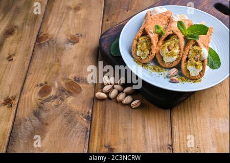 Cannoli Sizilien. Traditionelle italienische Süßspeise mit Ricotta und verschiedenen Füllungen. Essen auf einem Holzbrett. Köstliche Leckereien aus dem Süden Italiens. Speicherplatz kopieren. Stockfoto
