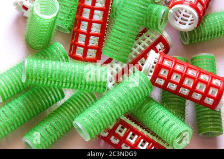 Haarauszieher auf dem rosa Hintergrund. Grüne und rote Keuler für Frisur. Stockfoto