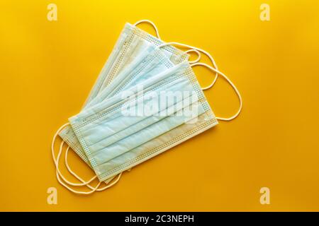 Gesichtsmasken auf gelbem Hintergrund, Draufsicht. Medizinische Sanitär-OP-Masken, Anti Staub atmungsaktive Einweg 3-Layer-Ohrbügel Mund Gesichtsmasken bieten Stockfoto