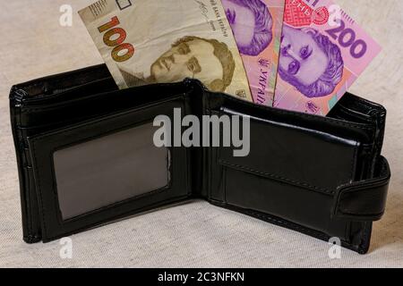 100 und 200 Griwna in einer schwarzen Brieftasche auf grauem Hintergrund. Stockfoto