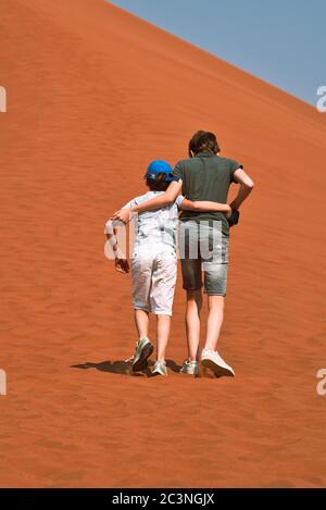 2 Brüder klettern auf einer Sanddüne in Namibia Stockfoto