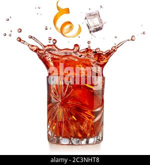 Orangenschale und Eis fallen in spritzendem negroni isoliert auf weiß Stockfoto