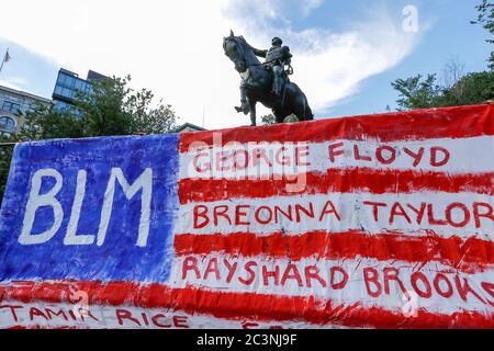 Während der Demonstration hängt eine künstlerische Darstellung einer amerikanischen Flagge mit Namen von Menschen, die von der Polizei getötet wurden, vor einer George Washington Statue. Hundertstel demonstrieren in New York gegen Präsident Trumps Faschist KKKKAMPAIN und Black Lives Matter march am Junienth-Wochenende. Die Demonstranten marschieren weiterhin gegen Polizeibrutalität und rassistische Ungerechtigkeit in ganz Amerika. Stockfoto