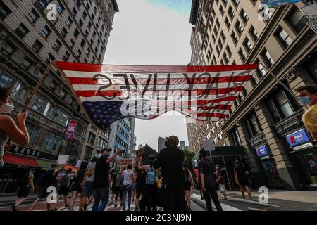 Während der Demonstration tragen die Demonstranten eine künstlerische Darstellung einer amerikanischen Flagge. Hundertstel demonstrieren in New York gegen Präsident Trumps Faschist KKKKAMPAIN und Black Lives Matter march am Junienth-Wochenende. Die Demonstranten marschieren weiterhin gegen Polizeibrutalität und rassistische Ungerechtigkeit in ganz Amerika. Stockfoto