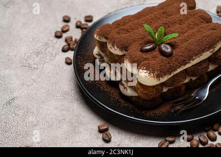 Klassisches Tiramisu Dessert auf Keramikplatte auf Betongrund Stockfoto