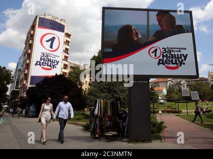 Das Paar hält die Hände, wenn es an den Plakaten der regierenden Serbischen Fortschrittspartei (SNS) des amtierenden Präsidenten Aleksandar Vucic ahea vorbeikommt Stockfoto