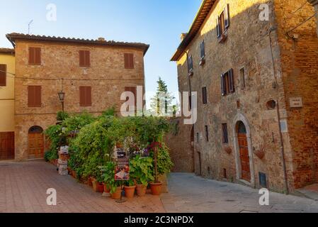 PIENZA, ITALIEN - 26. MAI 2017: Schöne schmale Straße mit Sonnenlicht und Blumen in dem kleinen magischen und alten Dorf Pienza, Val D'Orcia Toskana Stockfoto