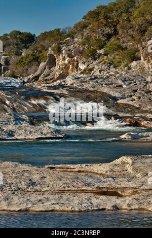 Kaskaden und Pools des Pedernales River mit Wanderern in der Ferne im Pedernales Falls State Park, Hill Country, Texas, USA Stockfoto