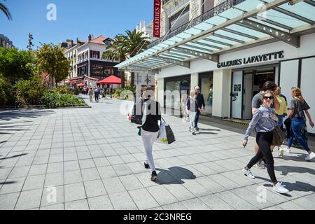 Biarritz, Frankreich - 17. Juni 2018: Place Georges Clemenceau, Frau, die mit Taschen in der Nähe der Schaufenster der Galeries Lafayette geht Stockfoto