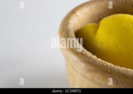 Frische Zitrone in einer Holzschale auf der rechten Seite, isoliert auf einem weißen Hintergrund Stockfoto