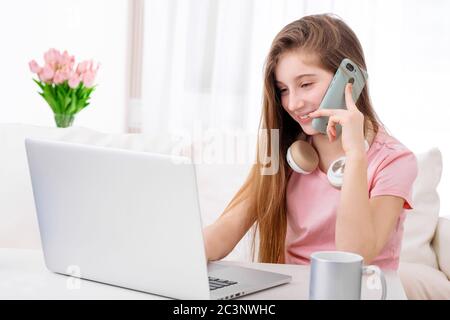 Liebenswert Mädchen, die Anrufe beim Sitzen vor offenen Laptop im Wohnzimmer Stockfoto