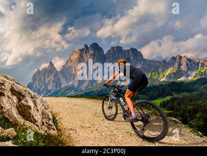 Touristisches Radfahren in Cortina d'Ampezzo, atemberaubende felsige Berge im Hintergrund. Frau auf dem MTB Enduro Flow Trail. Südtirol Provinz Italien, D Stockfoto