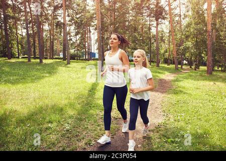 Laufen sportliche Mutter und Tochter. Frau und Kind joggen in einem Park. Outdoor-Sport und Fitness-Familie. Stockfoto