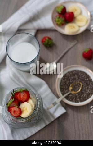 Gesunder veganer Chiasamen-Pudding in einem Einmachglas mit Erdbeere und Banane. Rustikales und dunkles Konzept Stockfoto