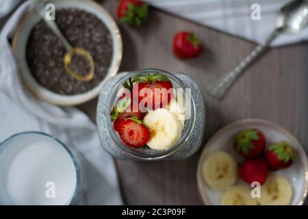 Gesunder veganer Chiasamen-Pudding in einem Einmachglas mit Erdbeere und Banane. Rustikales und dunkles Konzept Stockfoto