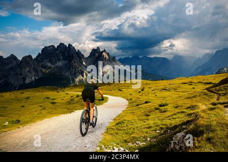 Touristisches Radfahren in Cortina d'Ampezzo, atemberaubende felsige Berge im Hintergrund. Frau auf dem MTB Enduro Flow Trail. Südtirol Provinz Italien, D Stockfoto