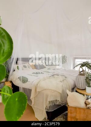 Helles weißes Schlafzimmer mit zahlreichen Zimmerpflanzen und Tageslicht Stockfoto