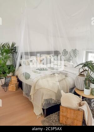 Helles weißes Schlafzimmer mit zahlreichen Zimmerpflanzen und Tageslicht Stockfoto