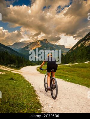 Touristisches Radfahren in Cortina d'Ampezzo, atemberaubende felsige Berge im Hintergrund. Frau auf dem MTB Enduro Flow Trail. Südtirol Provinz Italien, D Stockfoto