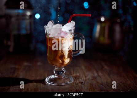 Kalter Kaffee mit Milch auf einem Holzbrett. Blauer unscharfer Hintergrund Stockfoto