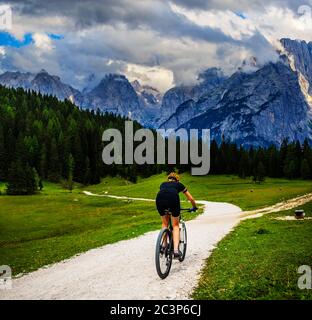 Touristisches Radfahren in Cortina d'Ampezzo, atemberaubende felsige Berge im Hintergrund. Frau auf dem MTB Enduro Flow Trail. Südtirol Provinz Italien, D Stockfoto