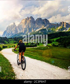 Touristisches Radfahren in Cortina d'Ampezzo, atemberaubende felsige Berge im Hintergrund. Frau auf dem MTB Enduro Flow Trail. Südtirol Provinz Italien, D Stockfoto