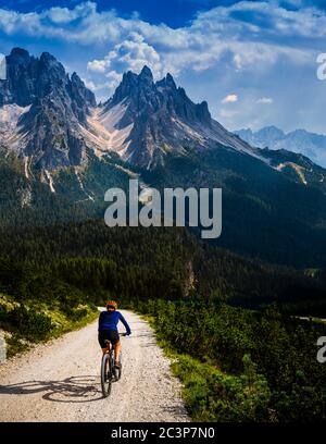 Touristisches Radfahren in Cortina d'Ampezzo, atemberaubende felsige Berge im Hintergrund. Frau auf dem MTB Enduro Flow Trail. Südtirol Provinz Italien, D Stockfoto