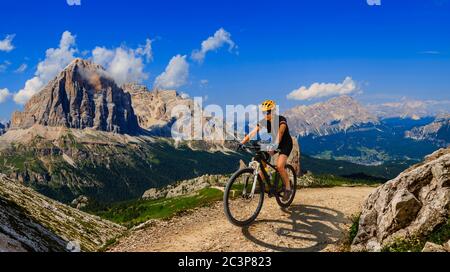 Touristisches Radfahren in Cortina d'Ampezzo, atemberaubende felsige Berge im Hintergrund. Frau auf dem MTB Enduro Flow Trail. Südtirol Provinz Italien, D Stockfoto