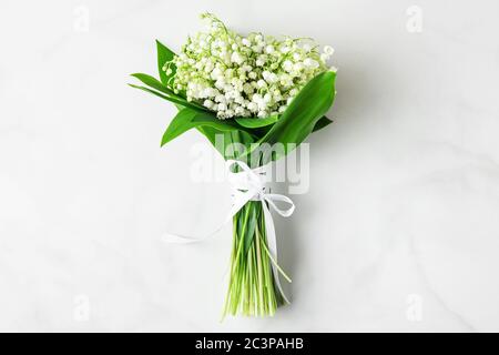 maiglöckchen Blumenstrauß auf weißem Marmorboden. Flache Lage. Draufsicht. Hochzeit oder Urlaub Hintergrund Stockfoto