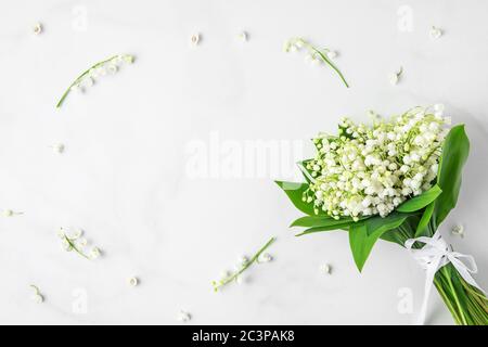 Blumenzusammensetzung. maiglöckchen Blumenstrauß auf weißem Marmorhintergrund. Flache Lage. Draufsicht mit Kopierraum. Hochzeit oder Urlaubskonzept Stockfoto