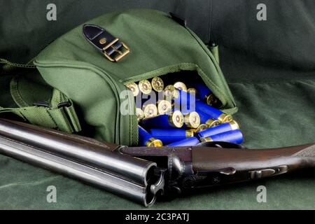 Schrotflinte mit Patronentasche und Patronen auf einem gewachsten Baumwoll-Outdoor-Mantel Stockfoto