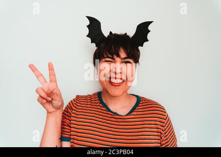 Selbstporträt einer kaukasischen Frau mit einem Fledermaus-förmigen Stirnband während Das Friedenszeichen tun Stockfoto