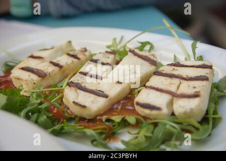 Drei geröstete Scheiben griechischer Halloumi-Käse, ein halbharter, unreiferer, gegerbter Käse, der aus einer Mischung aus Ziege- und Schafsmilch hergestellt wird. Serviert in einer Plate Stockfoto