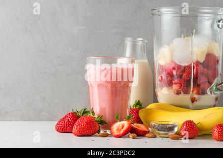 Glas Erdbeer und Banane Smoothie oder Milchshake mit frischen saftigen Zutaten im Mixer für die Herstellung von gesunden Getränken. Kochkonzept Stockfoto